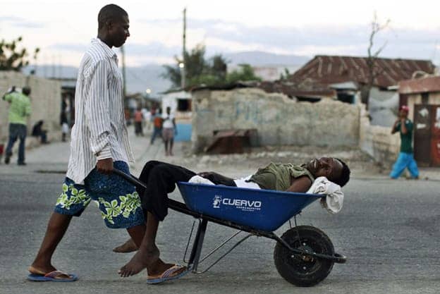 Man-carries-cholera-victim-in-wheelbarrow-Cite-Soleil-Port-au-Prince-Haiti-2010-by-Eduardo-Munoz-Reuters, UN capitalizing on cholera, playing both arsonist and fireman, World News & Views 
