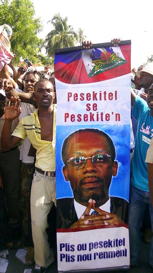 Aristide-summoned-to-court-support-banner-Persecuting-him-is-persecuting-us-050813, Stop the attacks on President Aristide and Haiti’s grassroots movement, World News & Views 