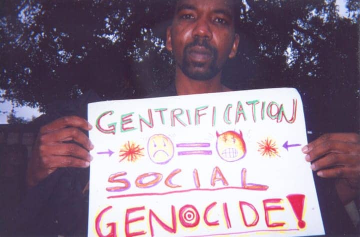 Black-man-holding-sign-Gentrification-Social-Genocide-web, Oakland City Council postpones vote on WOSP gentrification scheme, Local News & Views 