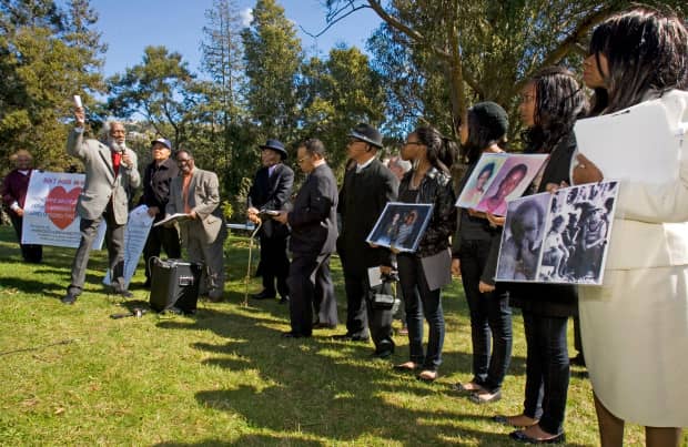 Jonestown-Memorial-Dick-Gregory-speaks-relatives-hold-photos-of-Peoples-Temple-victims-022811-by-D.-Ross-Cameron-San-Jose-Mercury-News, Wanda’s Picks for September 2017, Culture Currents 