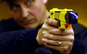 Blue-eyed-cop-aiming-taser-300x187, John Crew: Don’t be fooled by the POA, No on H, more aggressive use of Tasers, Local News & Views 