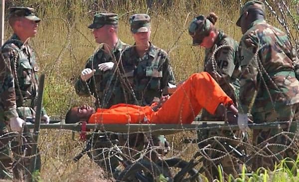 Guantanamo-hunger-striker-on-gurney-guards, Guantanamo Bay is hell on earth: an interview wit’ journalist Adam Hudson, Abolition Now! 
