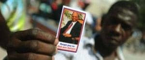 Haitian-protester-holds-Aristide-card-by-Hector-Retamal-300x125, Stop the political persecution of Aristide and Fanmi Lavalas once and for all, World News & Views 