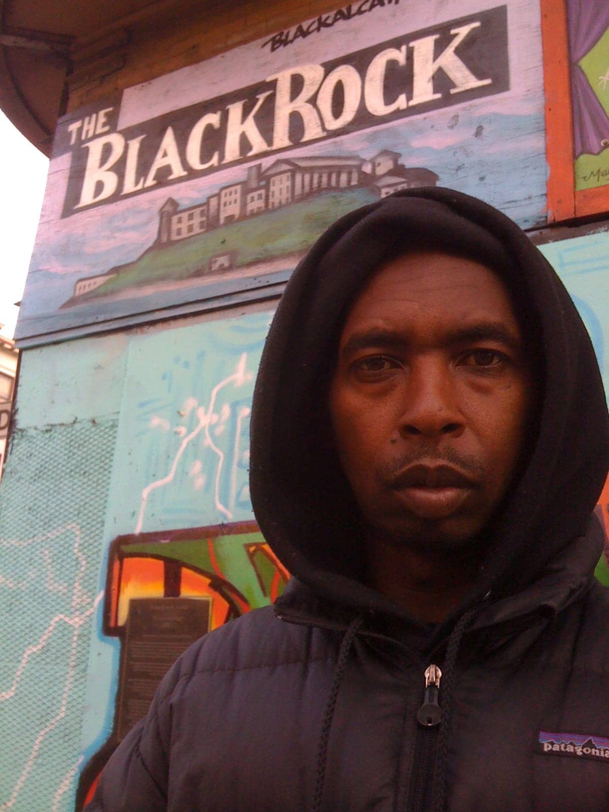 Kevin-Epps-stands-in-front-of-small-mural-for-The-Black-Rock, Filmmaker Kevin Epps releases new book, ‘Black Alcatraz’, Culture Currents 