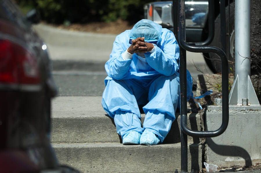 Black-healthcare-worker-sits-exhausted-on-steps-outside-Brooklyn-Hospital-Center-NY-040120-by-Tayfun-Coskun-Anadolu-Agency, If Medicare for All had been in force, hundreds of thousands killed by COVID would be alive, News & Views 