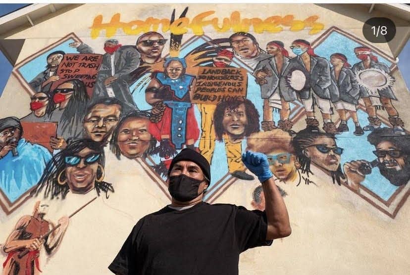 Israel-No.-1-in-front-of-the-mural-of-Homefulness-by-Rtystk-and-Ace-Robles-of-Oaklands-Kiss-My-Black-Arts-by-Tiny-e1643505007460, A poverty skola was born in a porta potty ‘cause there is no room at the inn – the herstory, News & Views 