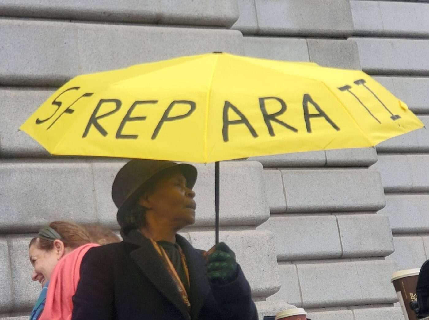 Community-Worker-Miss-Adrian-with-her-reparations-umbrella-1400x1043, Afatasi The Artist: 'In our case for reparations', World News & Views 