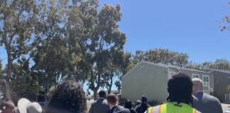 Kenisha Roach, left, and Oronde Sterling, right, walk just behind Mayor Daniel Lurie, center, on a tour of public housing in Hunters Point.