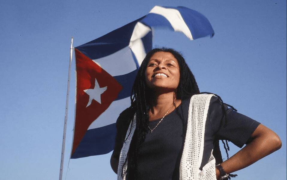 assata-shakur-smiling-in-front-of-cuban-flag, Assata Shakur, socialism and the fight for liberation, World News & Views assata-shakur-smiling-in-front-of-cuban-flag, Assata Shakur, socialism and the fight for liberation, World News & Views