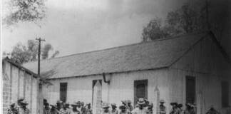 Black prisoners organize for dignity in Angola, Louisiana’s modern-day plantation Many black men in stripped prison clothes, behind barbed wire fence.