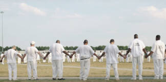 Alabama’s Black Sea: Limestone’s B-Yard Multiple Prisoners dressed in white holding hands stretched in a large circle.