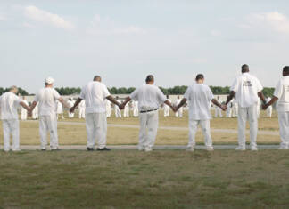 Alabama’s Black Sea: Limestone’s B-Yard Multiple Prisoners dressed in white holding hands stretched in a large circle.