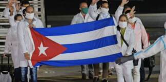 Turning its back on Cuba: Government of Guyana sells its soul People walking holding cuban flag.