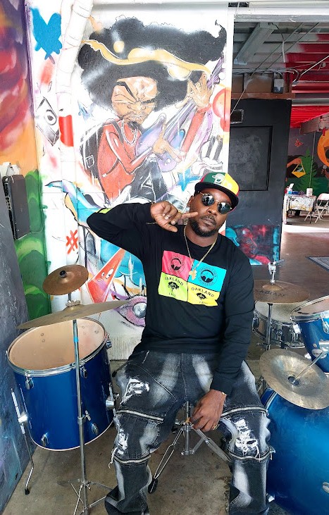 dre-in-front-of-drums-pic-and-mural-obsidiian, Obsidian Healing Camp is rejuvenating minds in deep West Oakland, Culture Currents Featured dre-in-front-of-drums-pic-and-mural-obsidiian, Obsidian Healing Camp is rejuvenating minds in deep West Oakland, Culture Currents Featured